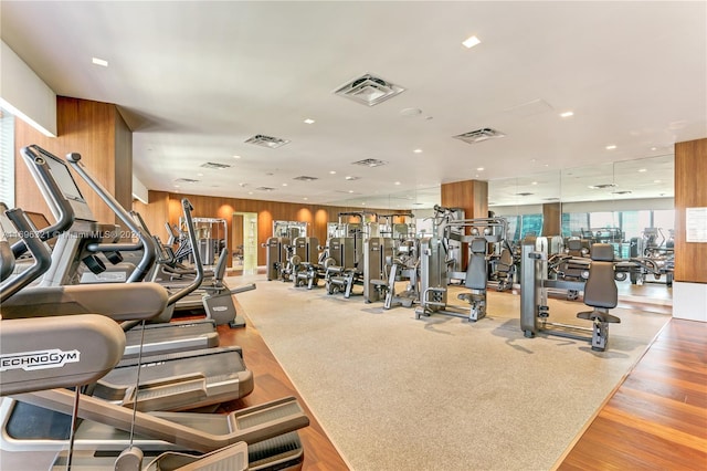 workout area with wooden walls and light hardwood / wood-style flooring