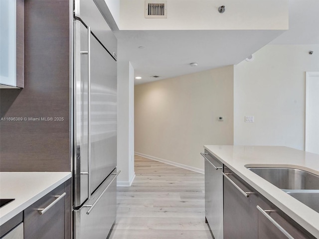 kitchen featuring stainless steel appliances, sink, and light wood-type flooring