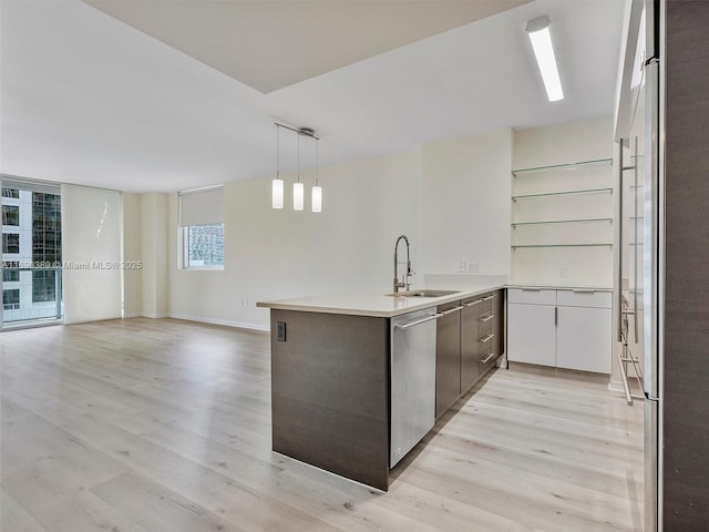 kitchen with sink, light hardwood / wood-style flooring, appliances with stainless steel finishes, hanging light fixtures, and kitchen peninsula