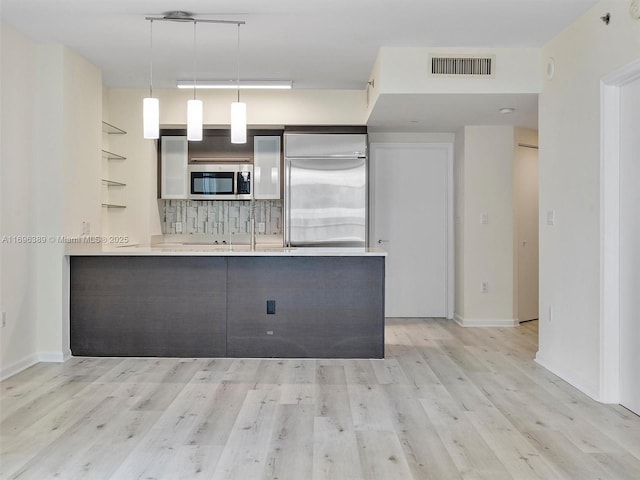 kitchen featuring pendant lighting, decorative backsplash, light hardwood / wood-style floors, kitchen peninsula, and stainless steel appliances