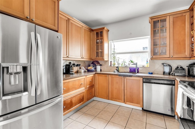 kitchen with backsplash, light tile patterned flooring, sink, and stainless steel appliances