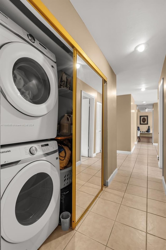 clothes washing area featuring stacked washing maching and dryer and light tile patterned floors