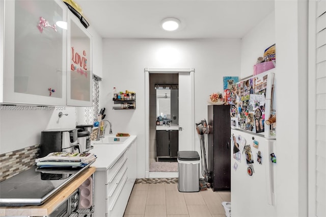 kitchen with white cabinetry, sink, stainless steel stovetop, and white refrigerator