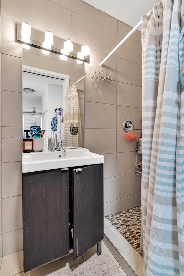 bathroom with a shower with shower curtain, vanity, and tile walls