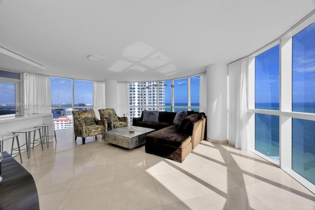 tiled living room featuring a water view, a wall of windows, and a wealth of natural light