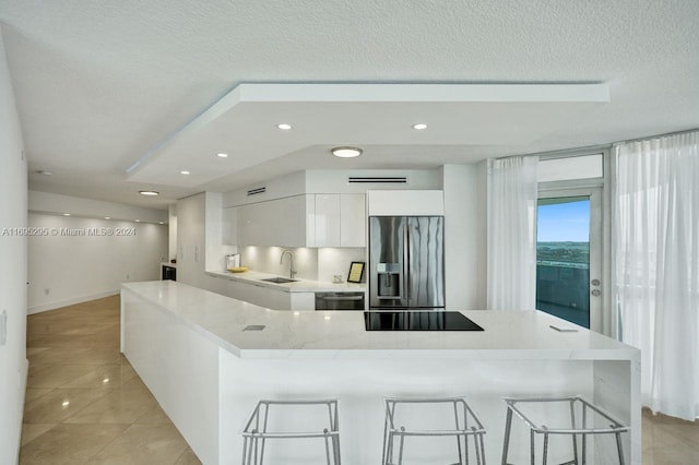 kitchen with white cabinetry, sink, stainless steel appliances, a breakfast bar area, and light tile patterned floors