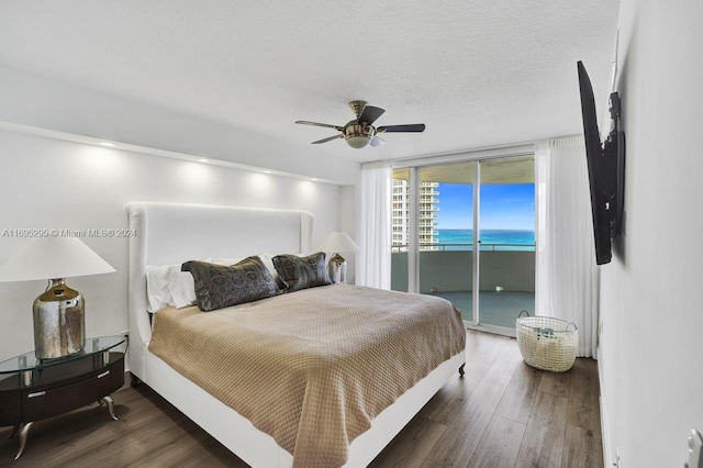 bedroom featuring floor to ceiling windows, dark wood-type flooring, access to outside, ceiling fan, and a textured ceiling