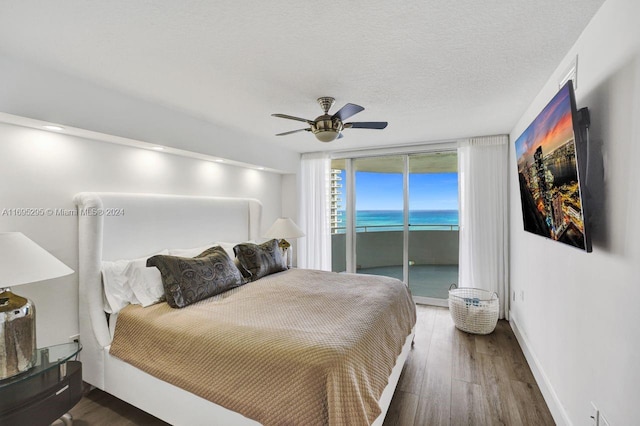 bedroom with floor to ceiling windows, access to exterior, ceiling fan, dark wood-type flooring, and a textured ceiling