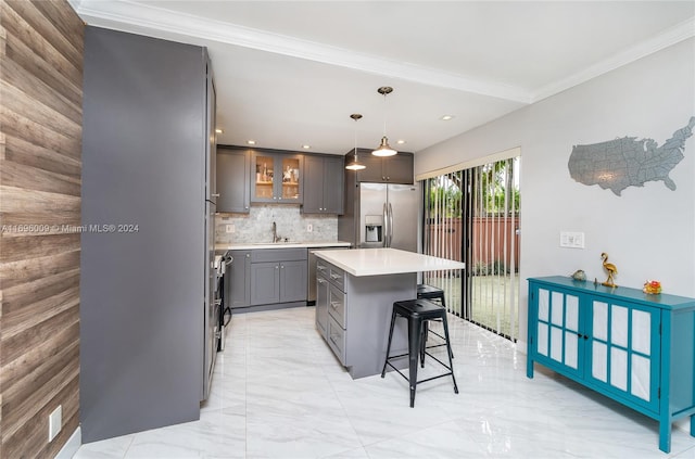 kitchen featuring decorative backsplash, appliances with stainless steel finishes, ornamental molding, decorative light fixtures, and a kitchen island