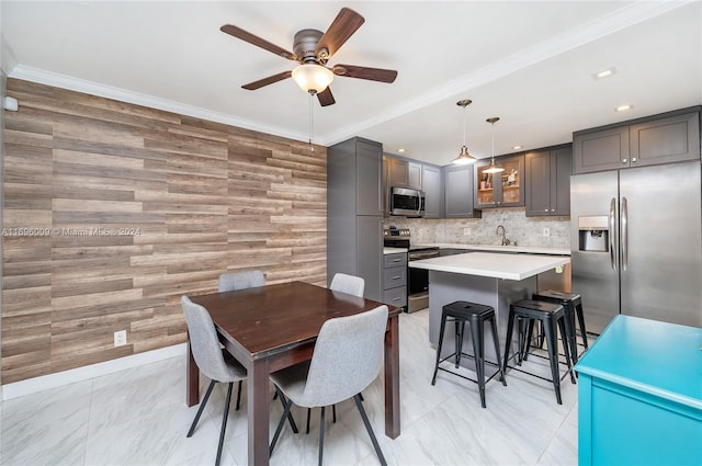 dining room with sink, ceiling fan, ornamental molding, and wood walls