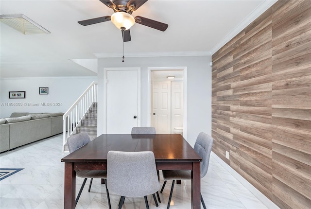 dining space with wooden walls, ceiling fan, and ornamental molding