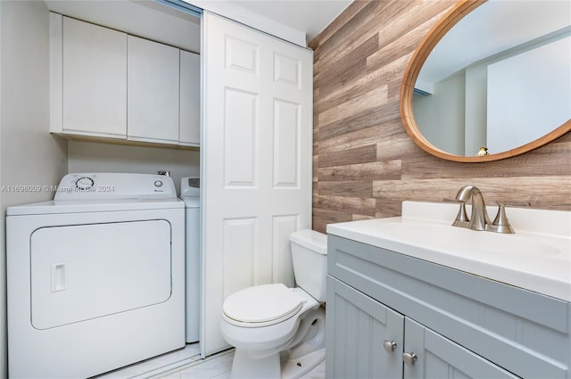 bathroom with washer / clothes dryer, wooden walls, vanity, and toilet