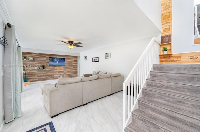 living room with wood walls, crown molding, and ceiling fan