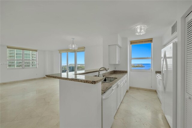 kitchen with white cabinetry, sink, kitchen peninsula, white appliances, and a water view