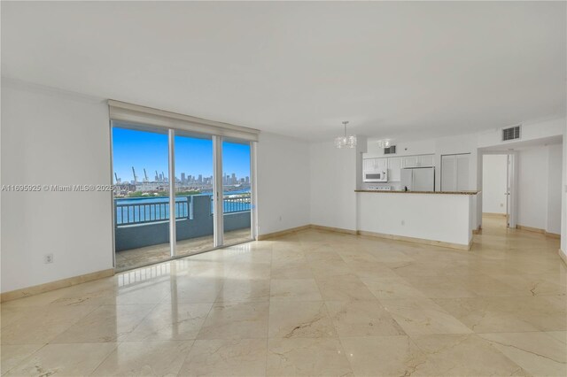 spare room featuring floor to ceiling windows, a water view, and a notable chandelier