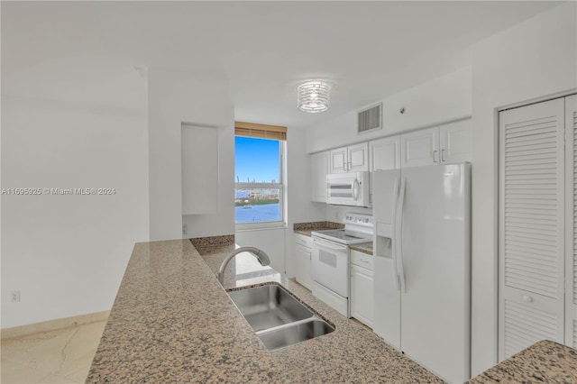 kitchen featuring kitchen peninsula, white appliances, sink, a water view, and white cabinetry