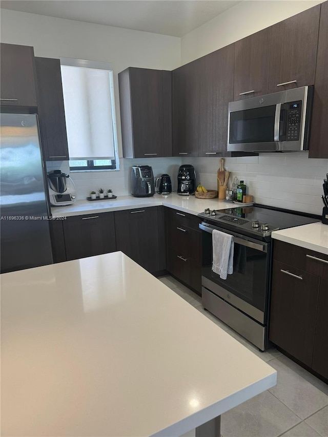 kitchen featuring decorative backsplash, appliances with stainless steel finishes, light tile patterned floors, and dark brown cabinets