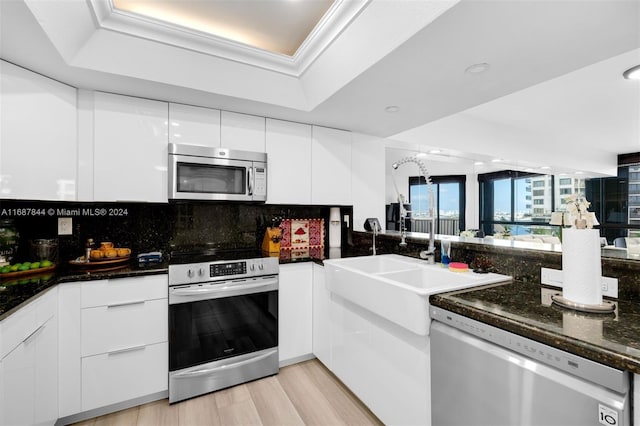 kitchen featuring backsplash, white cabinets, sink, light hardwood / wood-style flooring, and stainless steel appliances