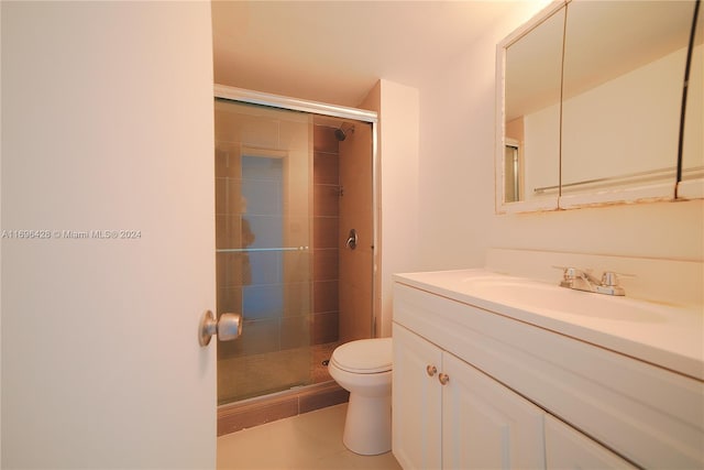 bathroom featuring tile patterned flooring, vanity, toilet, and an enclosed shower