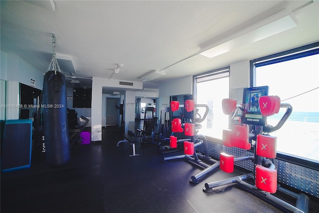 gym with a water view and a textured ceiling