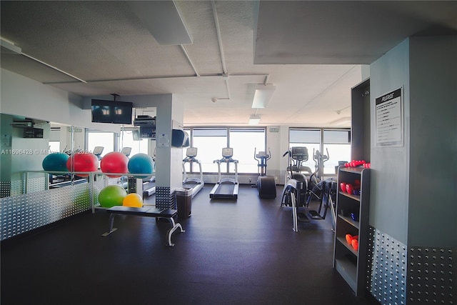 gym featuring a healthy amount of sunlight and a textured ceiling