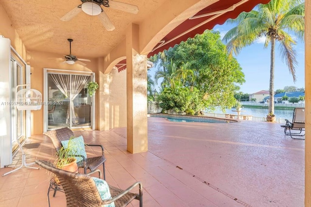 view of patio with ceiling fan and a water view