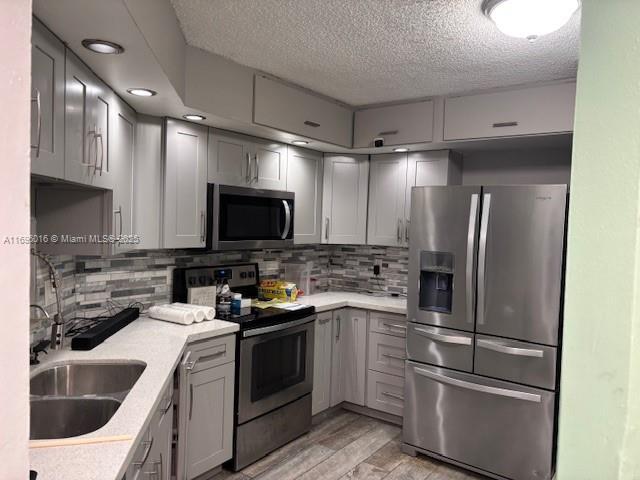 kitchen featuring appliances with stainless steel finishes, gray cabinets, and sink