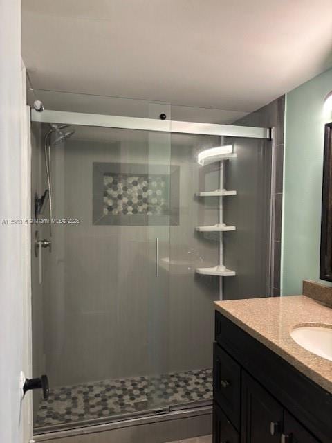 bathroom featuring a shower with door and vanity