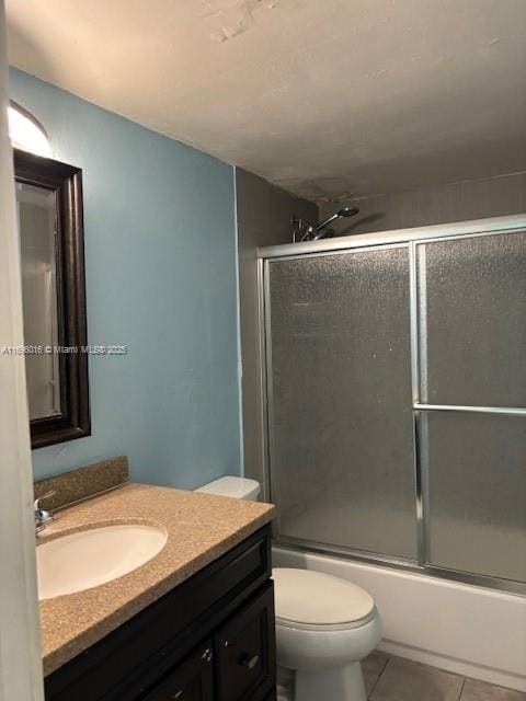 full bathroom featuring tile patterned flooring, shower / bath combination with glass door, vanity, and toilet