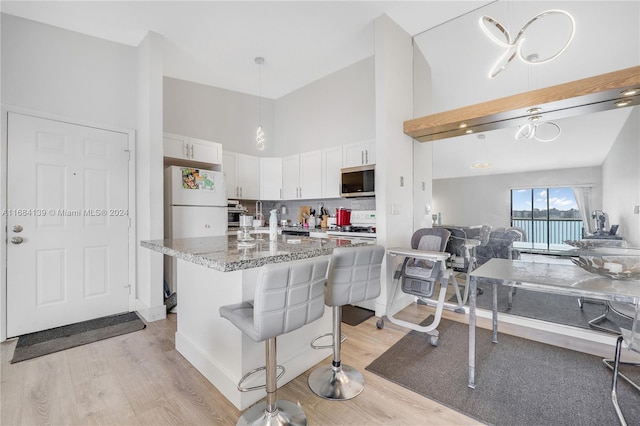 468 NE 206th Ln Unit 206, Miami, FL 33179 - kitchen featuring white appliances, light wood finished floors, light stone counters, a towering ceiling, and white cabinets