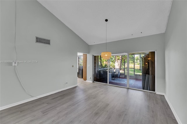 unfurnished room featuring hardwood / wood-style floors, a textured ceiling, and high vaulted ceiling