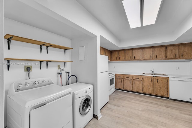 laundry area with light hardwood / wood-style floors, independent washer and dryer, and sink