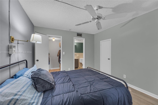 bedroom featuring ceiling fan, a textured ceiling, connected bathroom, and light hardwood / wood-style flooring