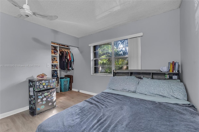 bedroom with wood-type flooring, a textured ceiling, a closet, and ceiling fan