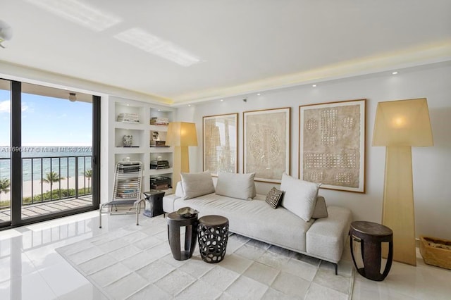 living room with built in features, a water view, and light tile patterned floors