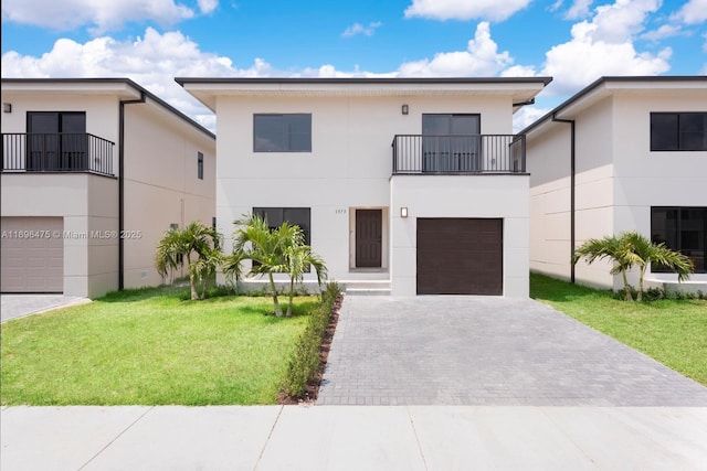 view of front of house with a front lawn, stucco siding, decorative driveway, a balcony, and a garage