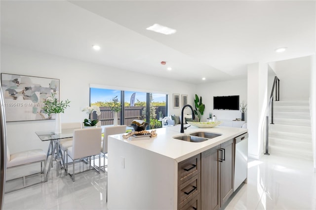 kitchen with a sink, a center island with sink, light countertops, recessed lighting, and stainless steel dishwasher