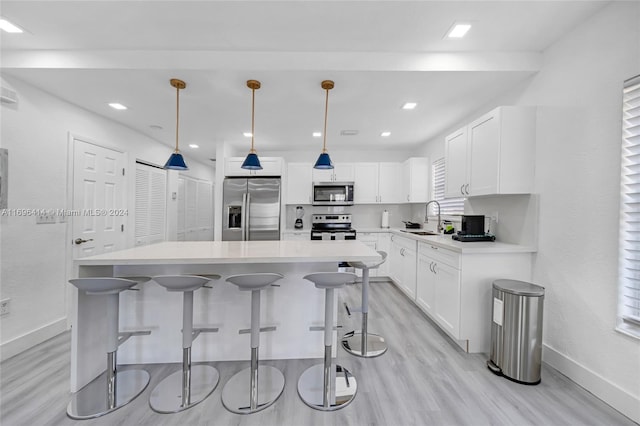 kitchen with white cabinets, sink, hanging light fixtures, a kitchen island, and stainless steel appliances