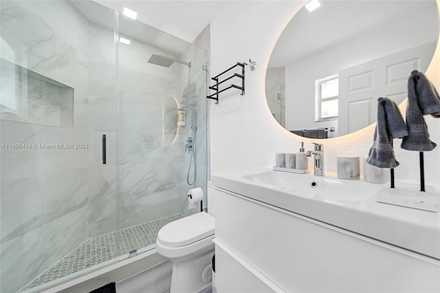 bathroom featuring vanity, toilet, and a shower with shower door