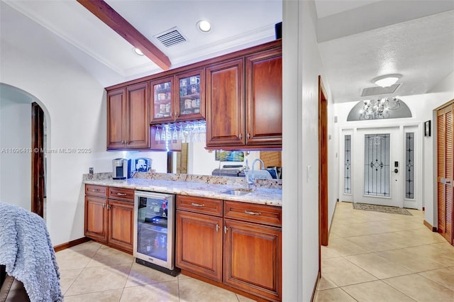 kitchen featuring sink, light stone counters, lofted ceiling with beams, light tile patterned floors, and beverage cooler