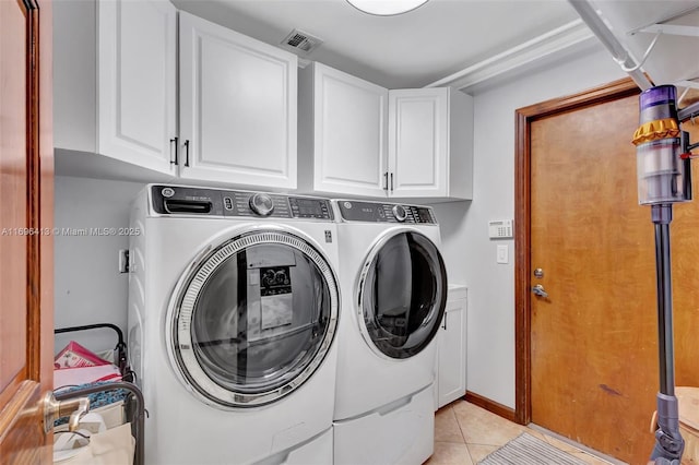 laundry area featuring cabinets, washer and clothes dryer, and light tile patterned floors