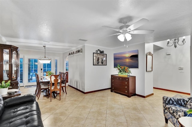 tiled living room with ceiling fan with notable chandelier and ornamental molding