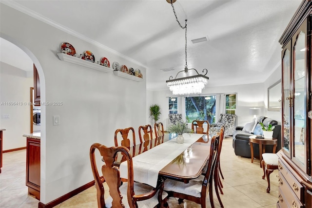 tiled dining space with crown molding, a notable chandelier, and washer / dryer