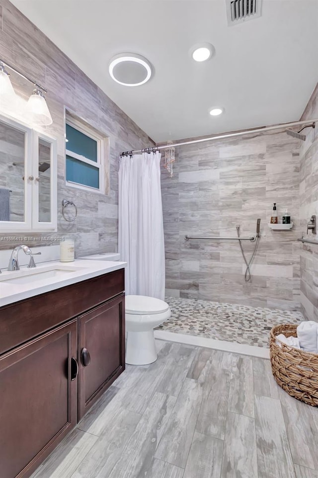 bathroom with tile walls, vanity, curtained shower, and toilet