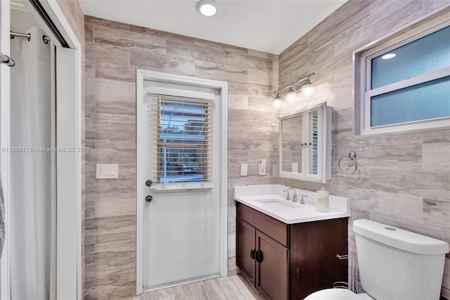 bathroom with vanity, toilet, and tile walls