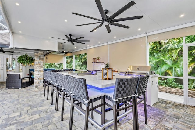 view of patio featuring grilling area, an outdoor kitchen, ceiling fan, and exterior bar