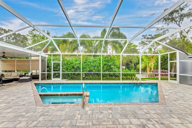 view of pool featuring an in ground hot tub, a patio, an outdoor hangout area, and glass enclosure