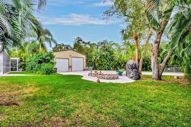 view of yard with a garage, a patio area, and an outdoor fire pit