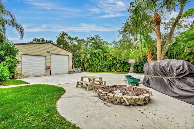 view of patio featuring a garage, an outbuilding, and a fire pit