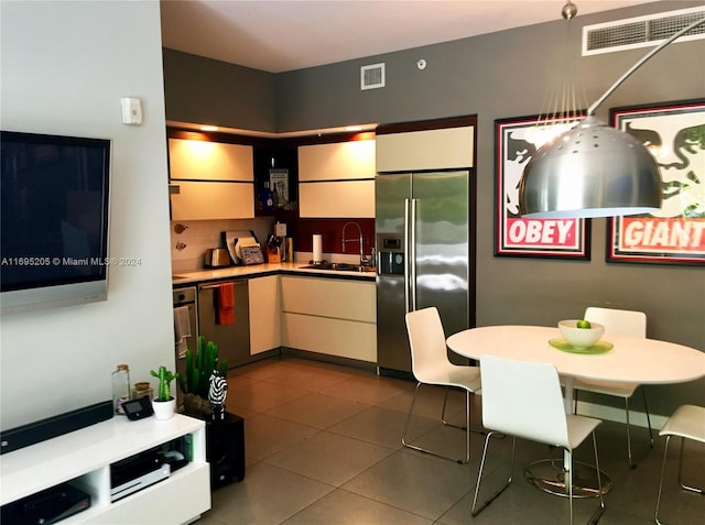 kitchen with stainless steel appliances, dark tile patterned floors, and sink